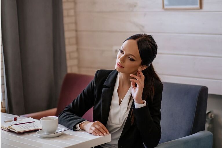 woman-sitting-on-cafe-sofa-holding-left-ear-using-left-hand